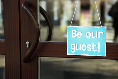 Image of Be Our Guest sign hanging on glass door outdoors