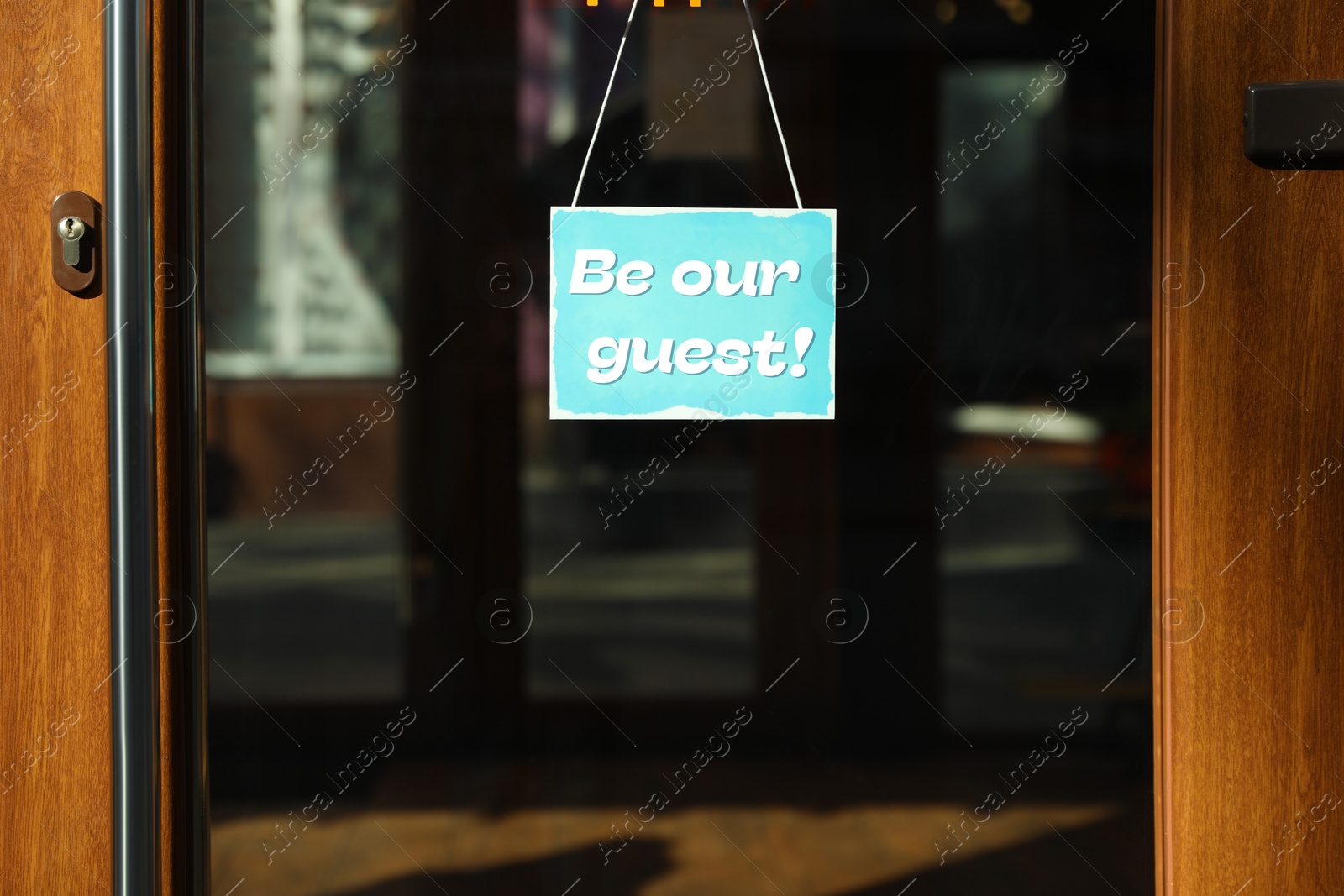 Image of Be Our Guest sign hanging on glass door outdoors