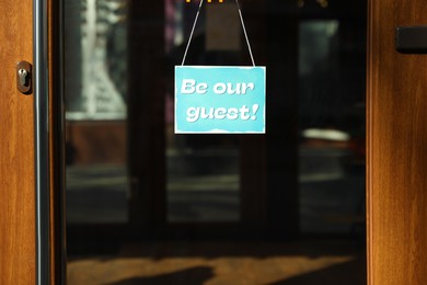 Image of Be Our Guest sign hanging on glass door outdoors