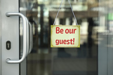 Image of Be Our Guest sign hanging on glass door outdoors