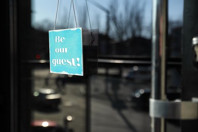 Image of Be Our Guest sign hanging on glass door outdoors