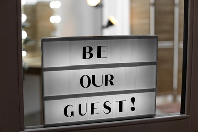 Image of Lightbox with phrase Be Our Guest on glass door indoors
