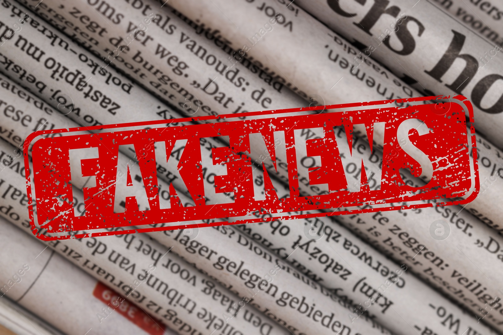 Red Fake News stamp and newspapers in different languages as background, closeup Image of Red Fake News stamp and newspapers in different languages as background, closeup