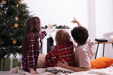 Photo of Family watching movie via video projector at home, back view