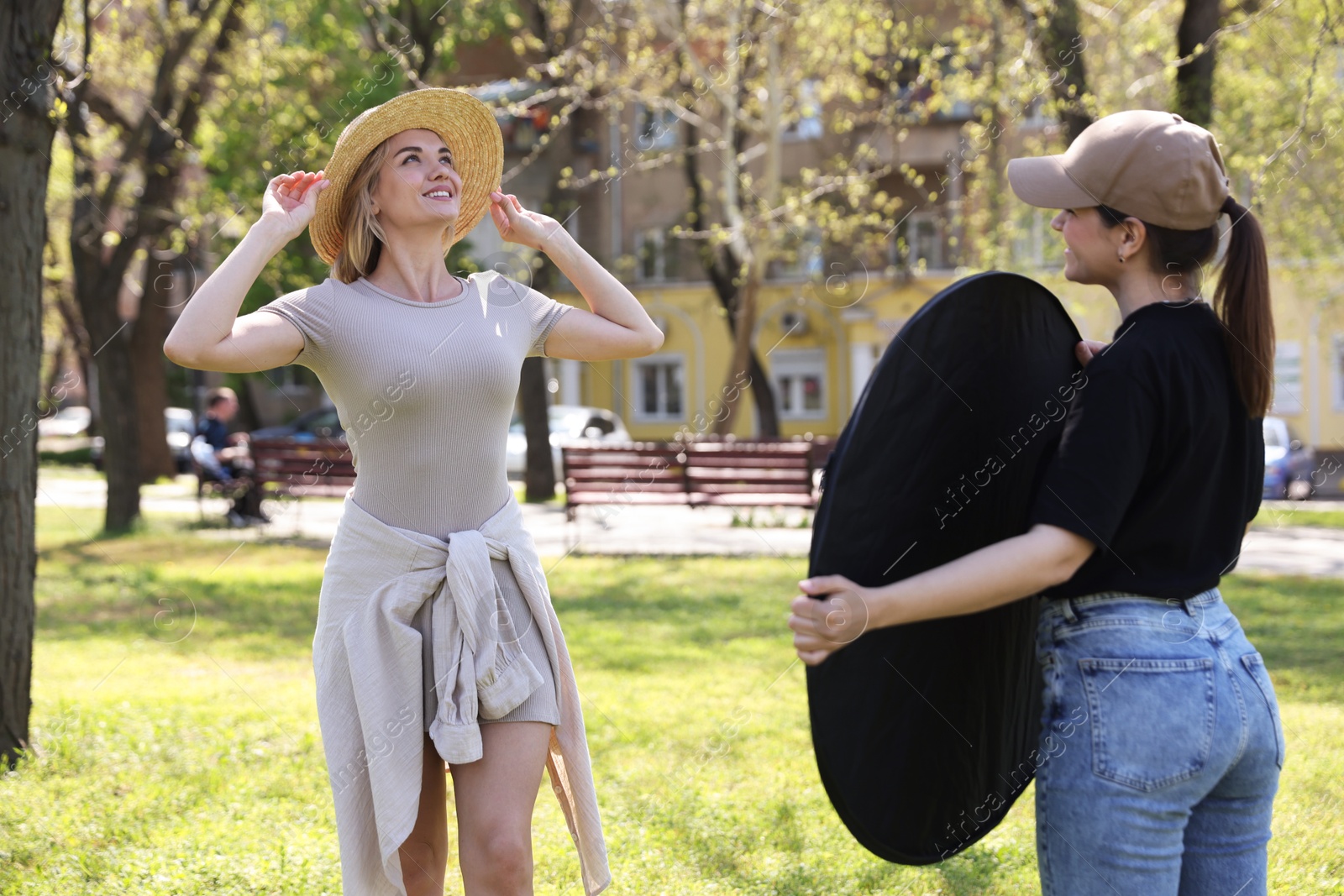 Professional photographer with reflector near model during shooting outdoors on sunny day Photo of Professional photographer with reflector near model during shooting outdoors on sunny day