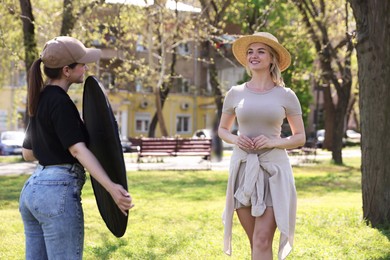 Photo of Professional photographer with reflector near model during shooting outdoors on sunny day