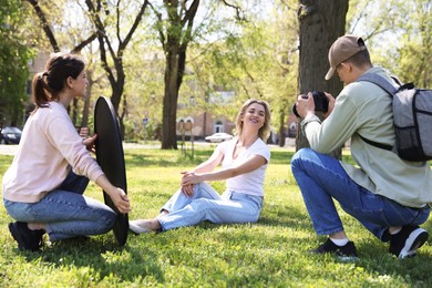 Photo of Professional photographers with reflector and camera near model during shooting outdoors on sunny day
