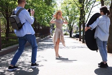 Photo of Professional photographers with reflector and camera near model during shooting outdoors on sunny day