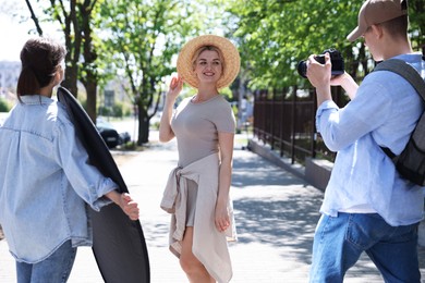 Photo of Professional photographers with reflector and camera near model during shooting outdoors on sunny day