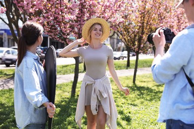 Photo of Professional photographers with reflector and camera near model during shooting outdoors on sunny day