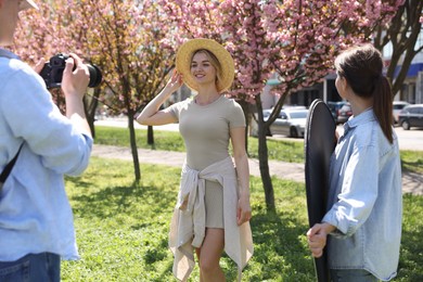Photo of Professional photographers with reflector and camera near model during shooting outdoors on sunny day