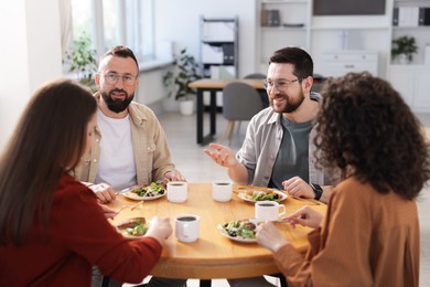 Photo of Colleagues chatting during lunch break in office