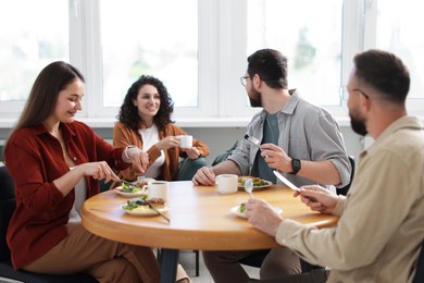 Photo of Colleagues chatting during lunch break in office