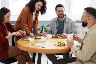 Photo of Colleagues chatting during lunch break in office