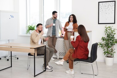 Photo of Colleagues chatting during coffee break in office