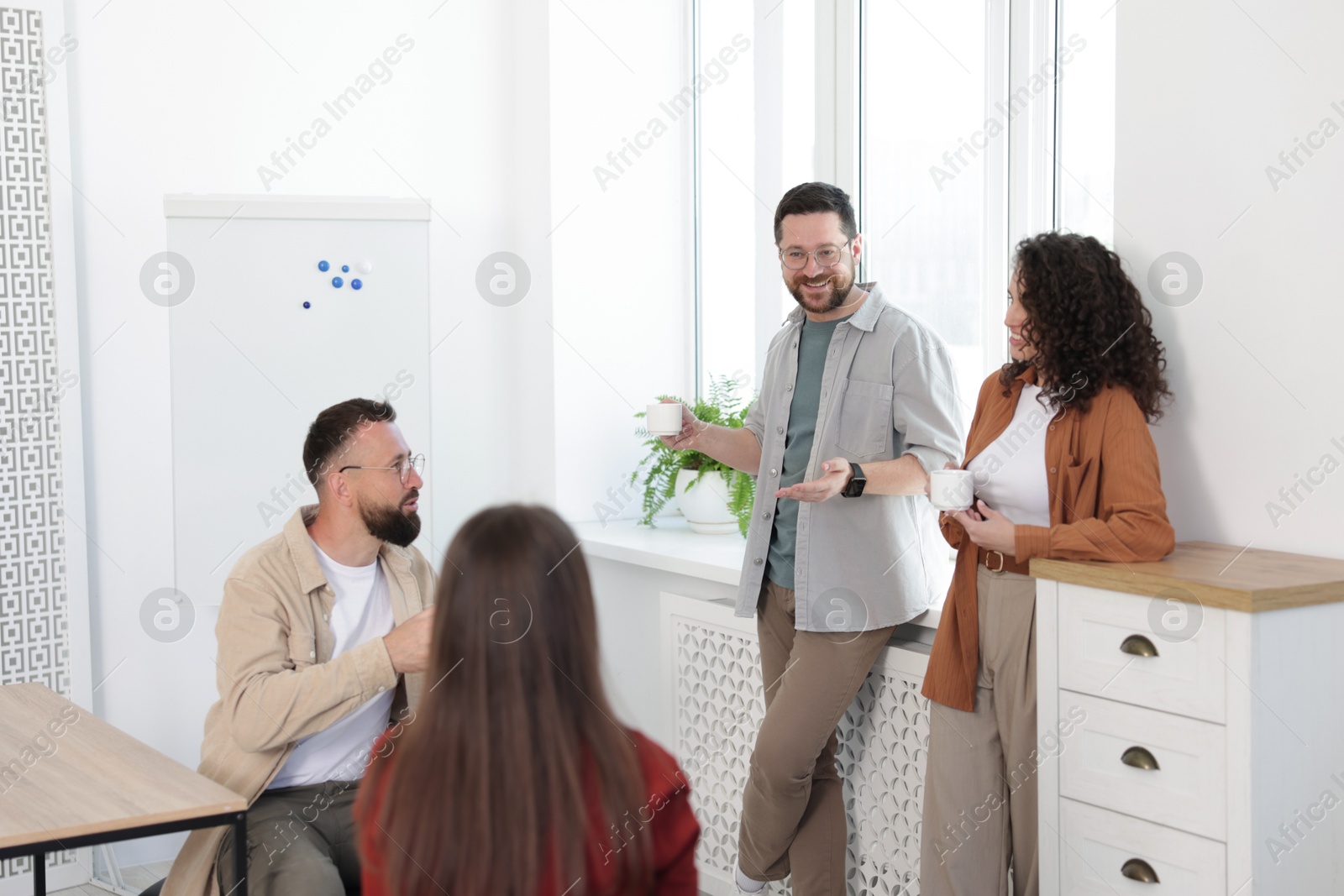 Colleagues chatting during coffee break in office Photo of Colleagues chatting during coffee break in office