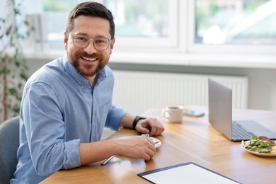 Photo of Man with meal at table during lunch break in office. Space for text