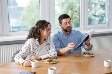 Photo of Colleagues eating and discussing work during lunch break in office