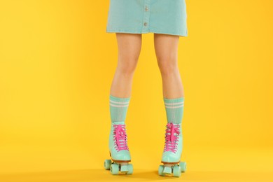 Photo of Woman in roller skates on orange background, closeup