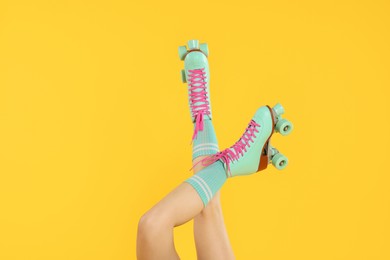 Photo of Woman in roller skates on orange background, closeup