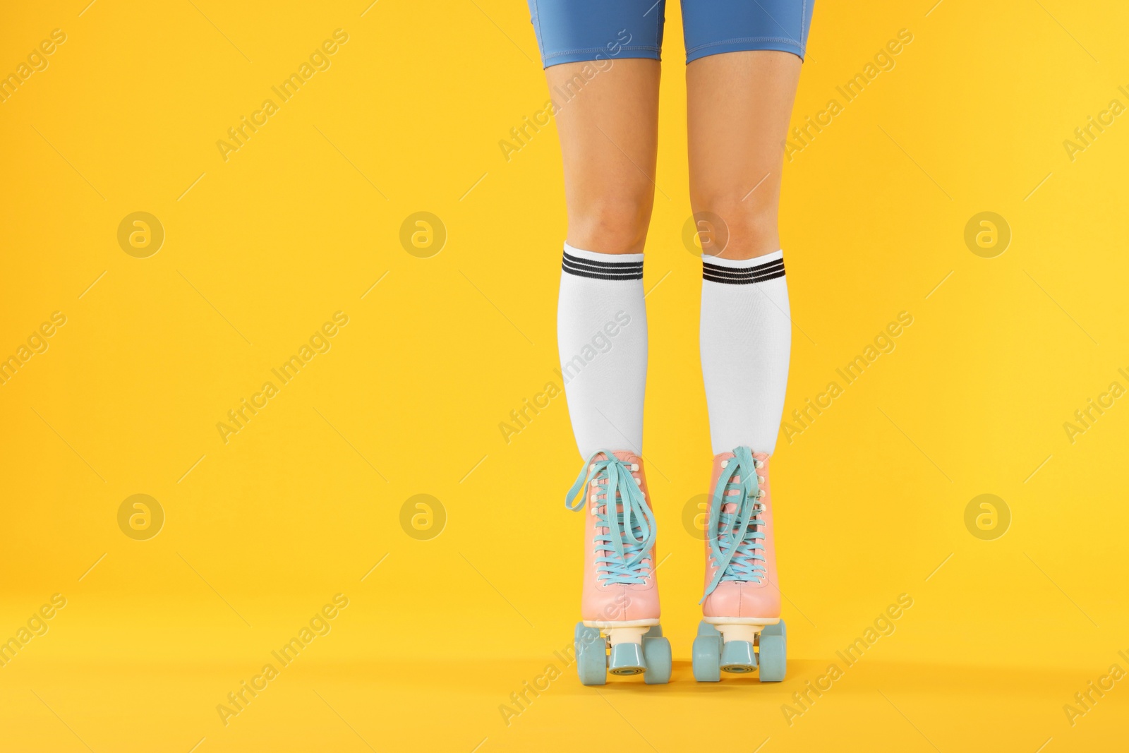 Woman in roller skates on orange background, closeup. Space for text Photo of Woman in roller skates on orange background, closeup. Space for text
