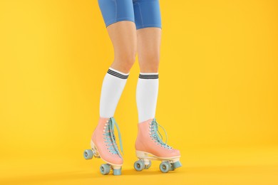 Photo of Woman in roller skates on orange background, closeup