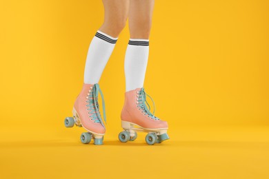 Photo of Woman in roller skates on orange background, closeup