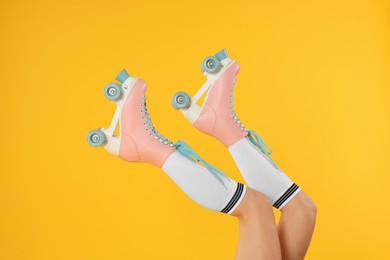 Photo of Woman in roller skates on orange background, closeup
