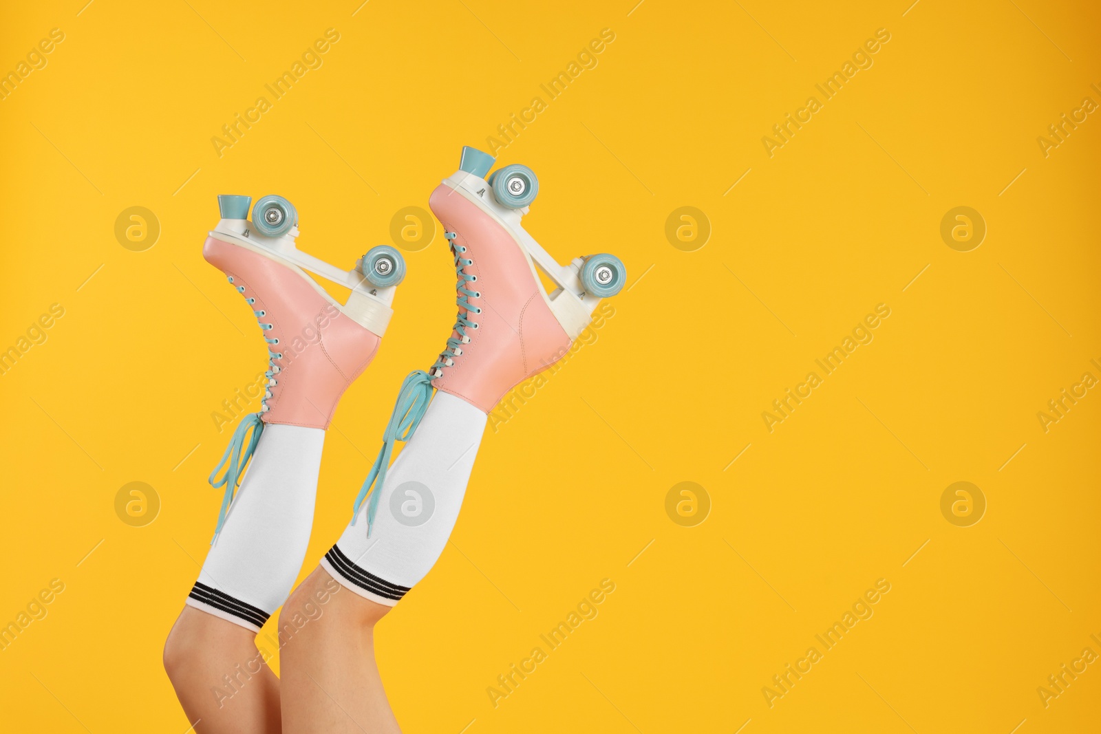 Woman in roller skates on orange background, closeup. Space for text Photo of Woman in roller skates on orange background, closeup. Space for text