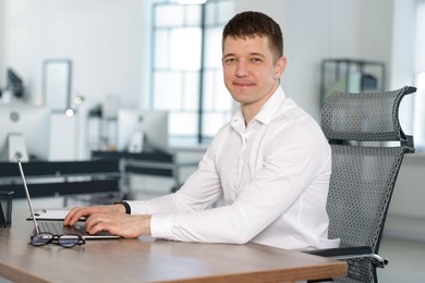 Photo of Man working on laptop at desk in office