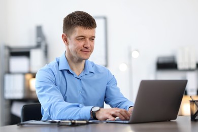 Photo of Man working on laptop at desk in office