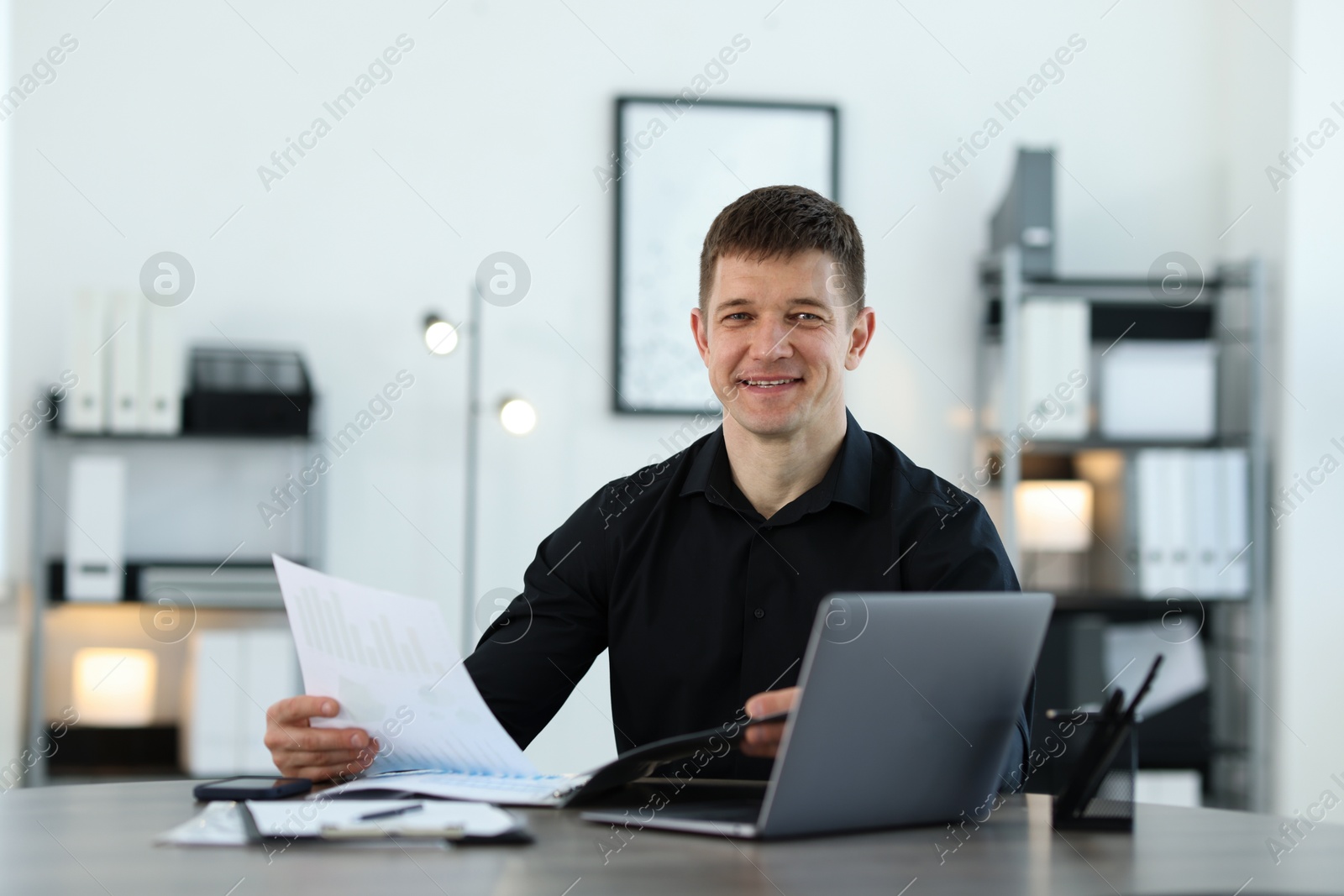 Photo of Handsome man working with documents at desk in office. Space for text
