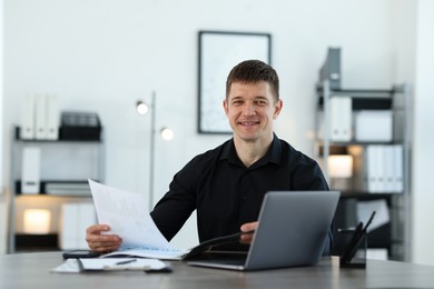 Photo of Handsome man working with documents at desk in office. Space for text