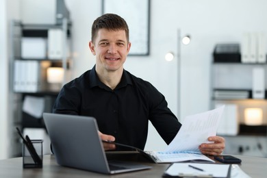 Photo of Handsome man working with documents at desk in office. Space for text