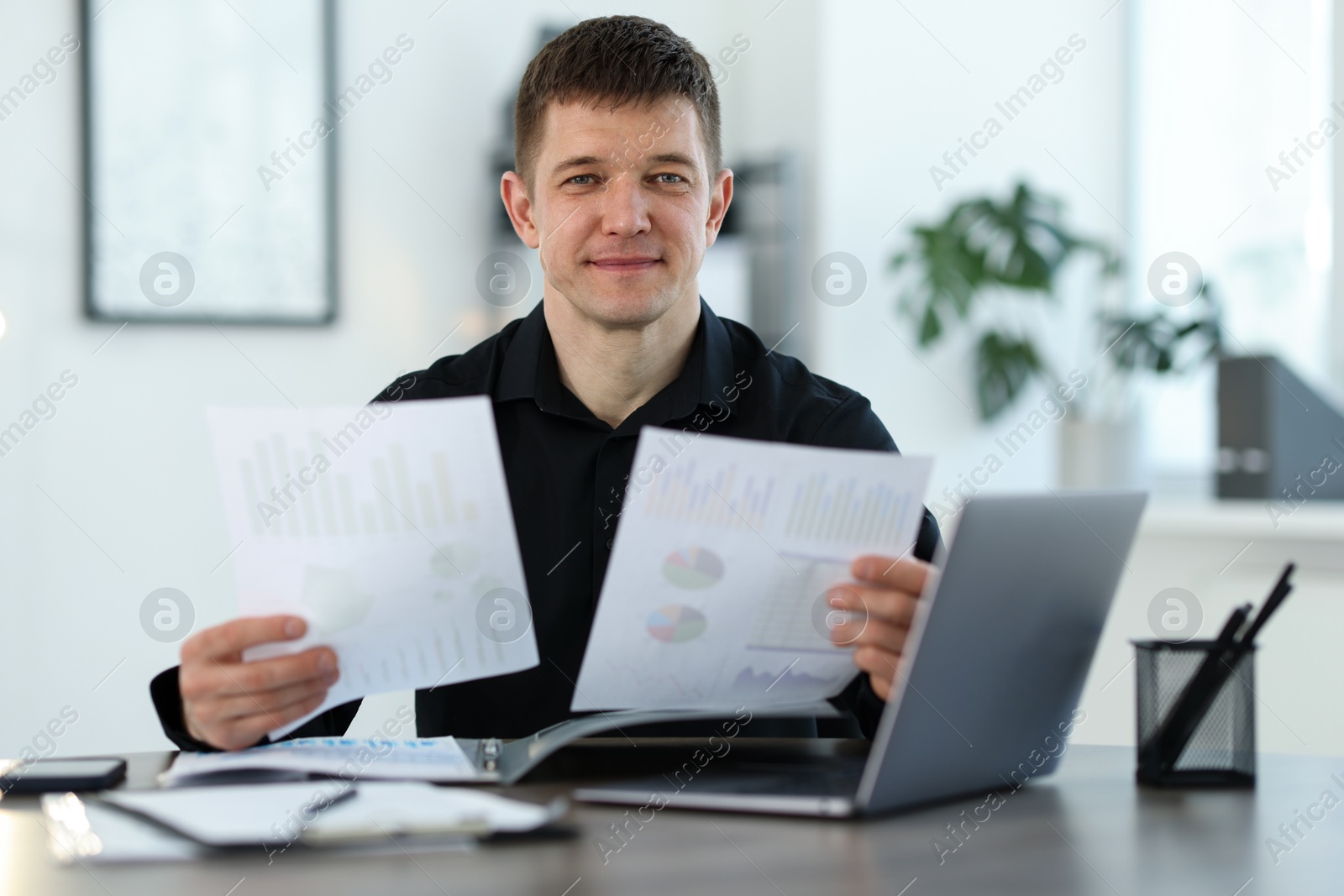 Handsome man working with documents at desk in office Photo of Handsome man working with documents at desk in office