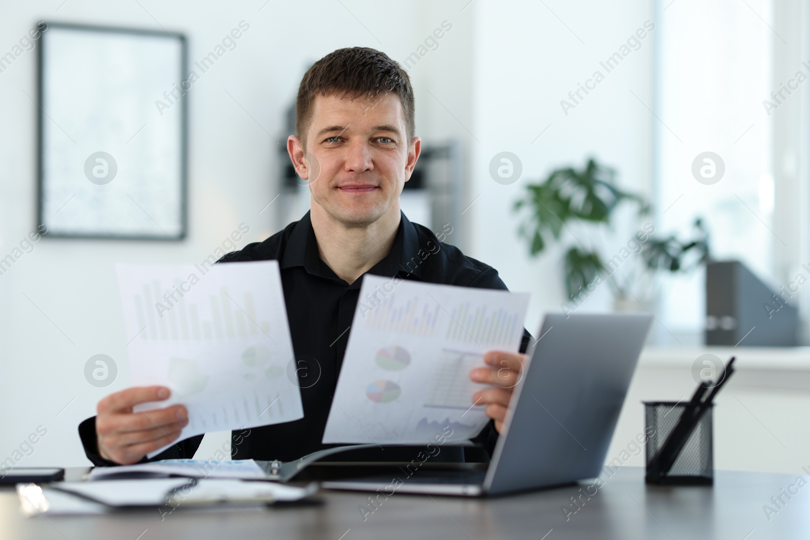 Handsome man working with documents at desk in office Photo of Handsome man working with documents at desk in office