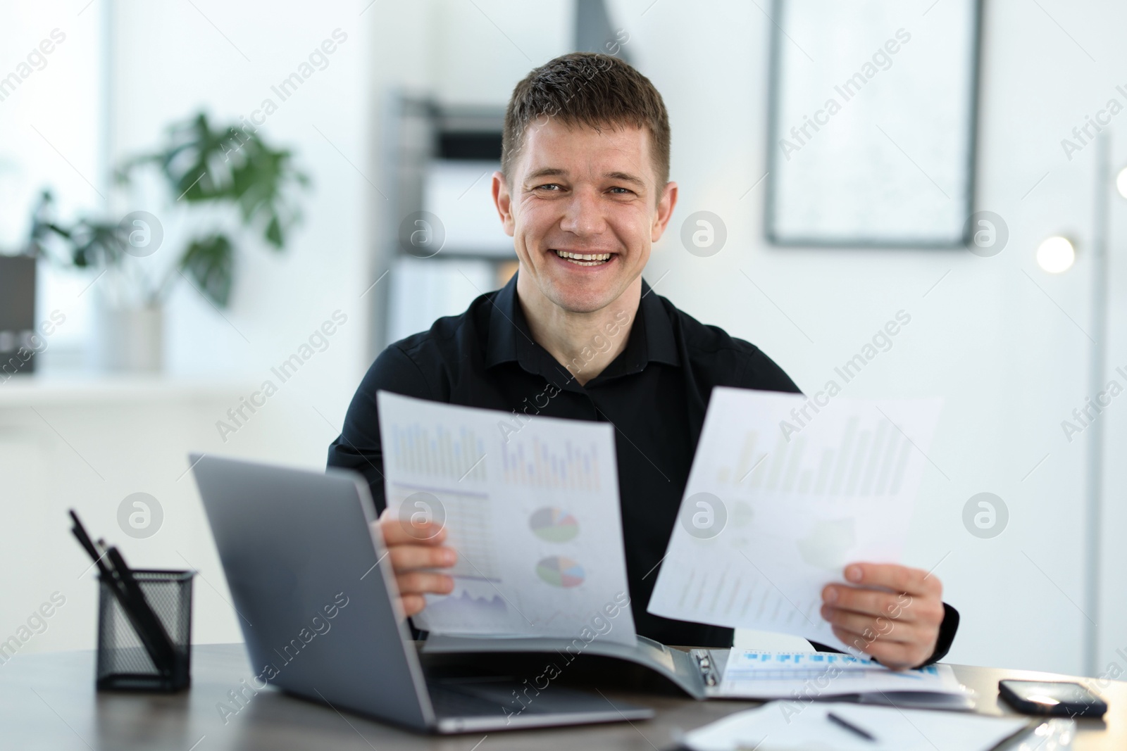 Handsome man working with documents at desk in office Photo of Handsome man working with documents at desk in office