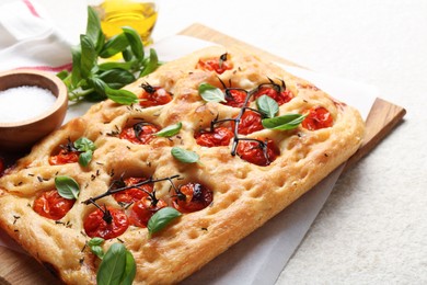 Photo of Delicious focaccia with tomatoes and spices on beige textured table, closeup