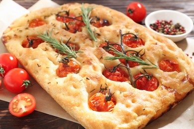 Photo of Delicious focaccia with tomatoes and spices on table, closeup