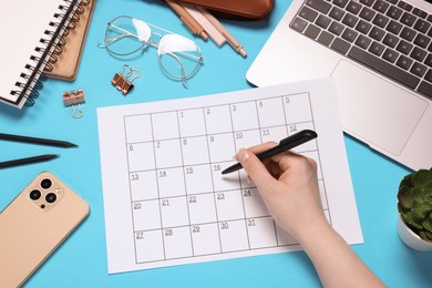 Photo of Woman with planner, stationery, laptop and smartphone on light blue background, top view