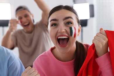Photo of Emotional sports fans watching game together indoors, selective focus