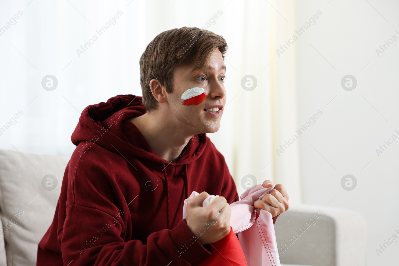 Emotional sports fan with flag of Poland watching game indoors, space for text Photo of Emotional sports fan with flag of Poland watching game indoors, space for text