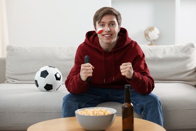 Photo of Sports fan with remote control watching game indoors