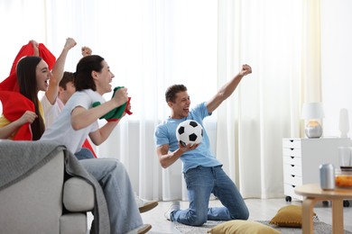 Photo of Emotional football fans watching game together indoors