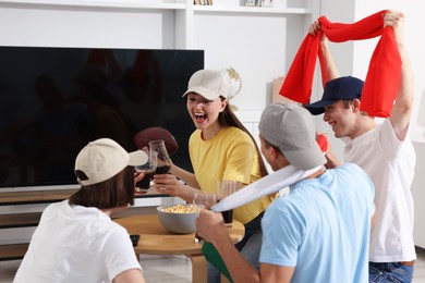 Photo of Emotional sports fans with drinks celebrating victory indoors
