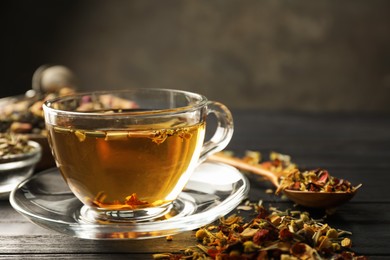 Photo of Refreshing herbal tea and dry leaves on black wooden table, closeup. Space for text