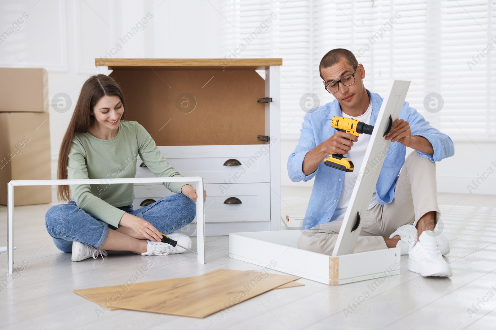 Happy couple assembling furniture on floor at home Photo of Happy couple assembling furniture on floor at home