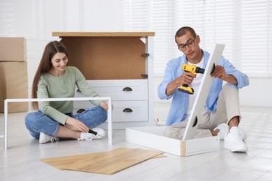 Photo of Happy couple assembling furniture on floor at home