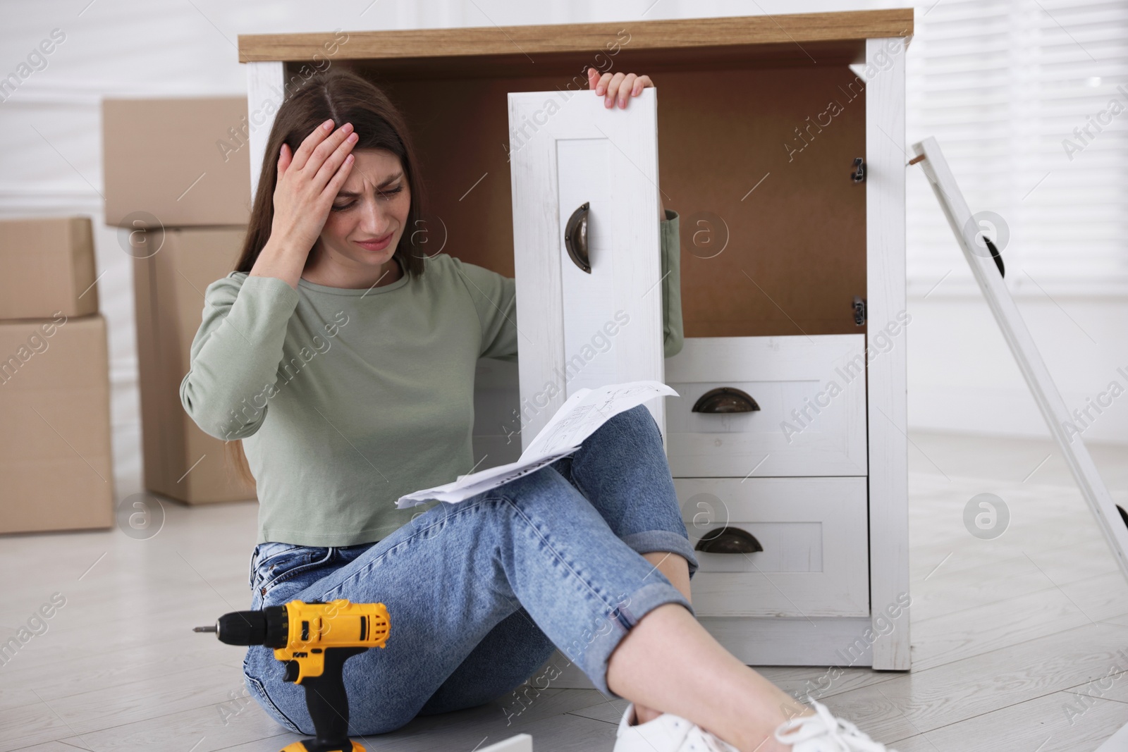 Upset woman with manual assembling furniture on floor at home Photo of Upset woman with manual assembling furniture on floor at home