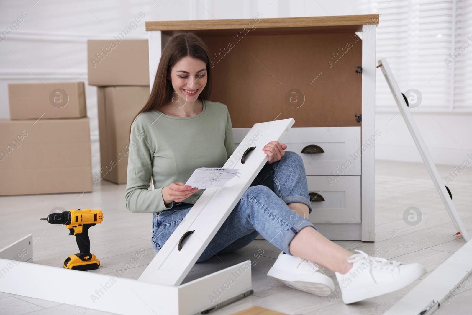 Smiling woman with manual assembling furniture on floor at home Photo of Smiling woman with manual assembling furniture on floor at home